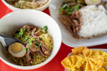 Portrait picture of Pork in noodles on red color table.