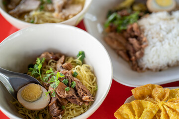 Portrait picture of Pork in noodles on red color table.