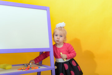 A small child chooses letters for words on a magnetic board. The concept of preschool education for children.