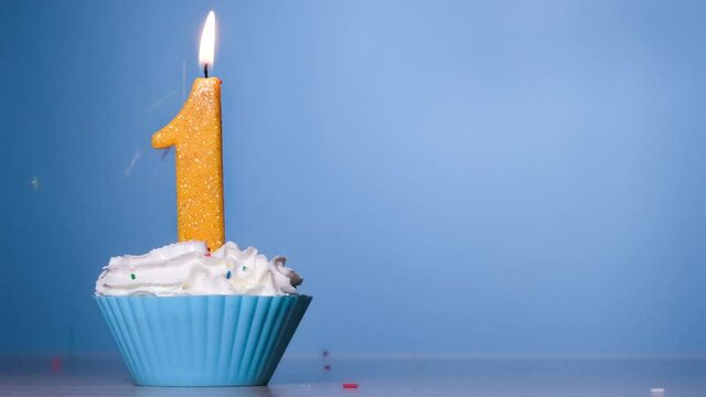 Birthday Cake With Burning Colorful Candle number one on Pastel Blue Background. 120 FPS. Slow motion anniversary banner with copy space
