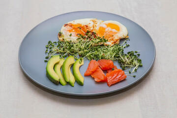 Fried eggs with avocado, salmon and micro green sprouts