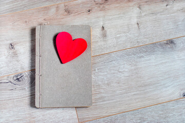 Craft notebook made of gray paper with a red cut out heart as a gift for Valentine's Day. Space for text