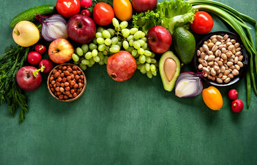 Frame of assorted fresh vegetables and fruits on green table. Food frame on green background with copy space.