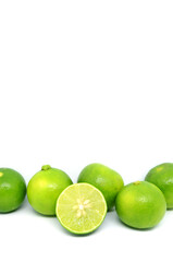 Cross section fresh key lime with heap of whole fruits in row on white background