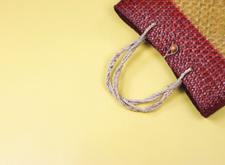 Fototapeta premium flat lay of straw bag or woven bag on yellow background.