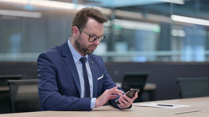 Middle Aged Businessman using Smartphone at Work