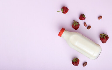 Fresh sweet strawberries,bottle of delicious dairy drink on the pink surface.Empty space