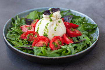 Salad with traditional italian burrata cheese with tomatos, basil and arugula