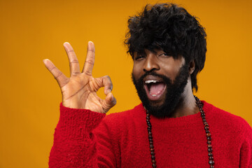 Black man showing ok sign against yellow background
