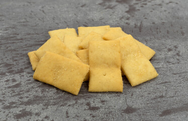 Serving of cheese and garlic snack crackers on a gray background side view.