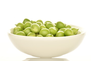 Several ripe green peas in a ceramic white dish, close-up, isolated on white.