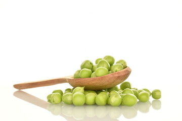Several ripe green peas with a spoon made of wood, close-up, isolated on white.