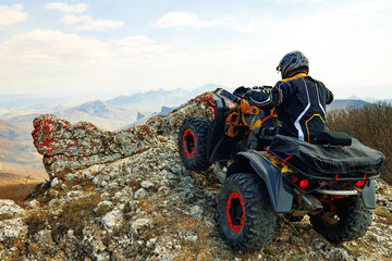 Man in helmet sitting on ATV quad bike in mountains © fotofabrika