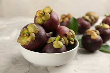 Fresh ripe mangosteen fruits on light grey table