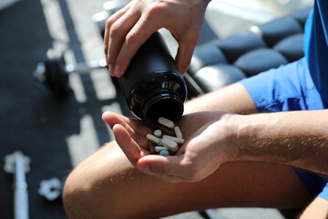 Sportsman with bottle of pills in gym, closeup. Doping concept