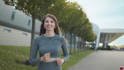 Young woman runner training in summer park city. Portrait of young and fit woman running and jogging alone on the empty street in city center wearing protective. Slow-motion shot