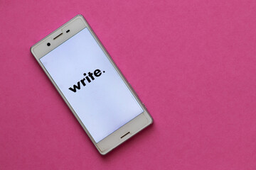 White cell phone on a pink background, the word 