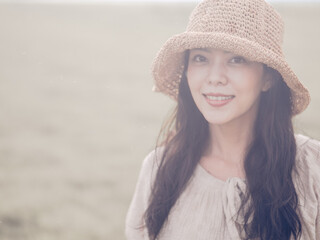 Cheerful asian young woman wear vintage dress with retro hat on the field at sunset