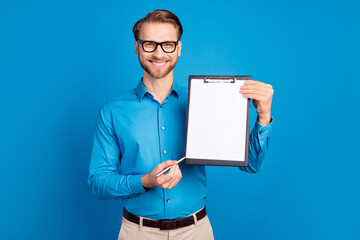 Photo of young man happy positive smile point pen clipboard document contract sign isolated over...