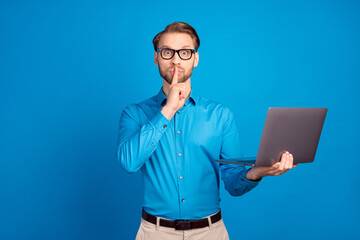 Photo of young man cover lips finger shh confident shut up keep secret use laptop isolated over...