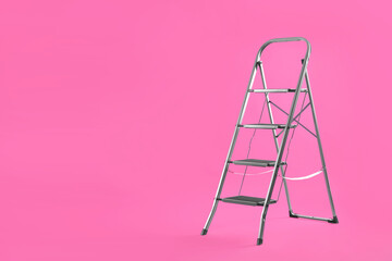 Modern metal stepladder on pink background. Space for text