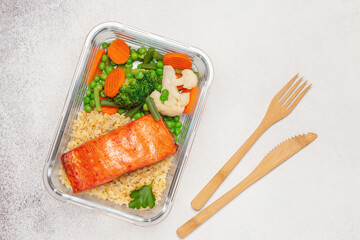 Salmon fillets with bulgur and vegetables in the container. Diet nutrition. Top view