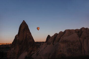 hovering hot air balloon over the mountains of cappadocia