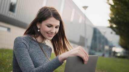 An urban, city busy woman business woman, entrepreneur typing on a laptop outside commercial complex. Young beautiful, attractive girl, female, lady corporate start up office employee working outdoor