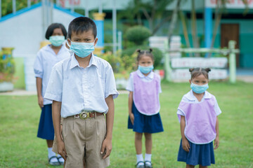 Surin, THAILAND - October 10, 2020:Thai students are sitting in a row to keep social distancing They are aware of Covid-19 and keep social distancing and wearing protective facemasks at school during 