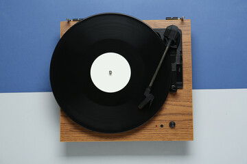 Turntable with vinyl record on color background, top view