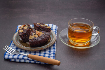 Pieces of fresh brownies on a plate with a teacup. Side view. Delicious chocolate pie. Dessert and relaxation concept