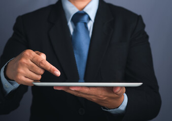 Hand of a businessman holding a digital tablet and touching on the screen. Close-up photo. Business and technology concept