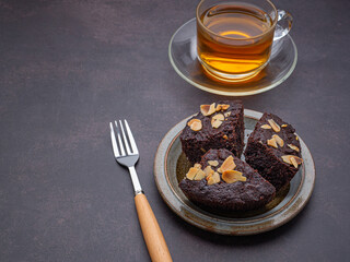 Pieces of fresh brownies on a plate with a teacup. Side view. Delicious chocolate pie. Dessert and relaxation concept