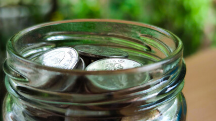 Close up coins in glass jar for money saving financial concept