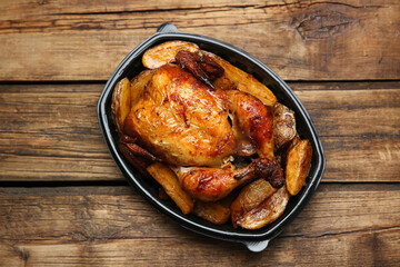 Delicious grilled chicken with potato in plastic container on wooden table, top view. Food delivery service