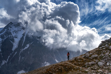 Journey. The girl stands and enjoys the view of the mountains and the epic sky with clouds