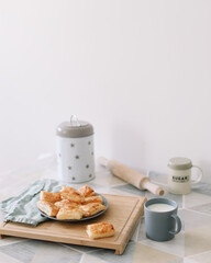 freshly baked homemade pastry on kitchen table. breakfast with puff buns and a glass of milk