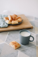 freshly baked homemade pastry on kitchen table. breakfast with puff buns and a glass of milk