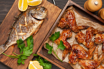 Chicken wings grill in teriyaki sauce with sesame in a wooden tray fish dorado on a wooden background. Top View