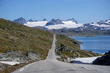 Norwegian straight road in the mountains with a glacier in the background