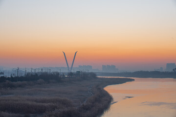The silhouette of a building with the light of dawn and a river flowing through it

