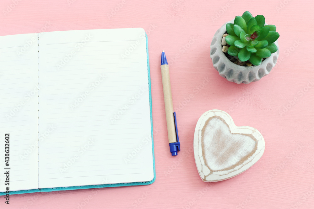 Poster empty open notebook and zen pebbles on pastel wooden background. copy space for text