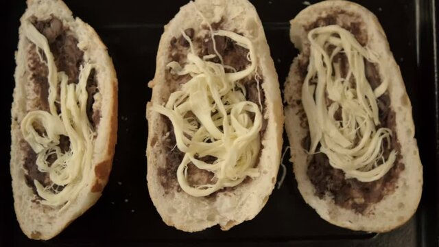 Three traditional Mexican molletes on a black tray