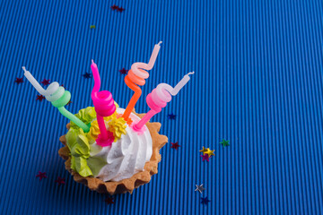 Creamy cupcake with candles colorful on blue background.
