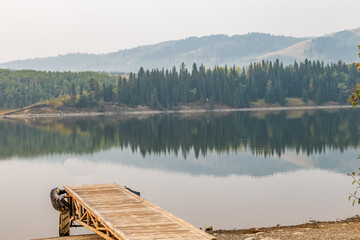 Reflections in the lake on a hazy morning. Chain Lakes Provincial Park, Alberta, Canada
