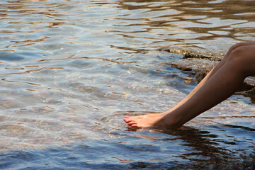 Sensual woman's legs in clean water splashes. Female legs on the beach against of ocean 