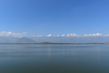 lake beside the mountains along with the clouds