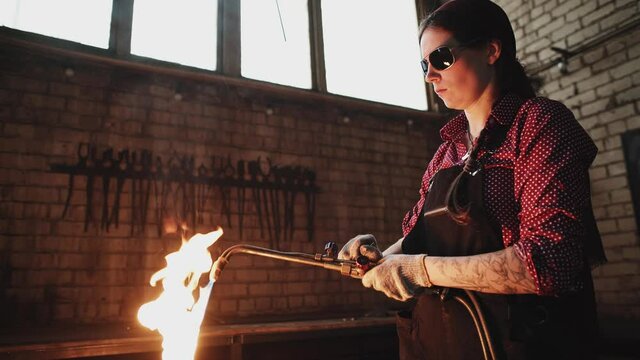 girl blacksmith works in her workshop. gas cutting of metal