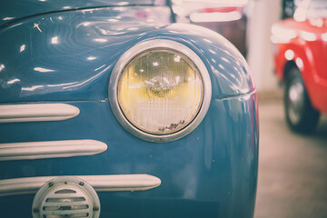 Close up round headlights of blue vintage classic car. Transportation and retro car collection concept.
