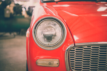 Close up round headlights of red vintage classic car. Transportation and retro car collection concept.